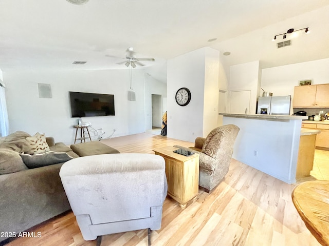 living area with vaulted ceiling, light wood-style floors, and ceiling fan