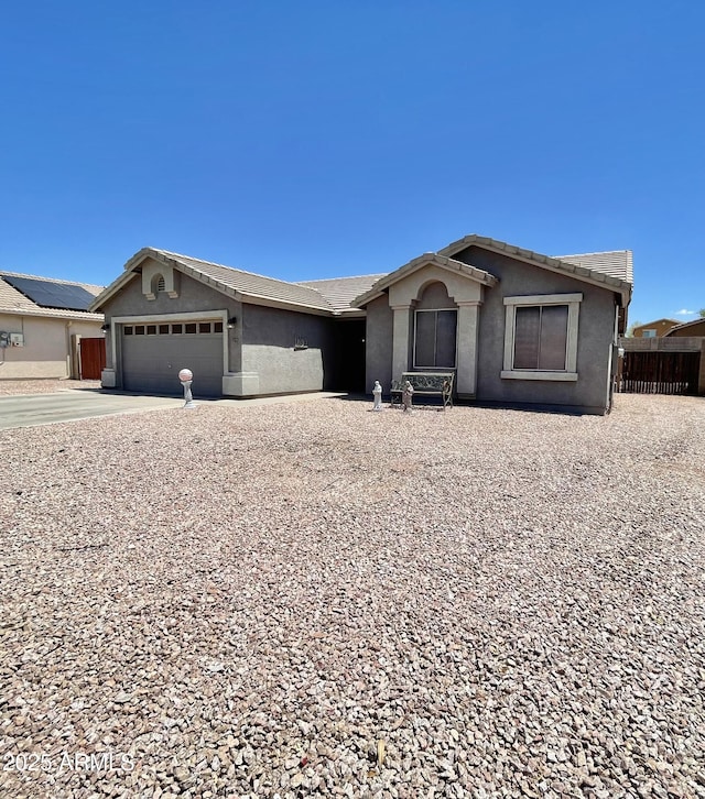 ranch-style house with stucco siding, a garage, fence, and driveway