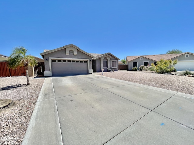 single story home with a garage, concrete driveway, stucco siding, and fence