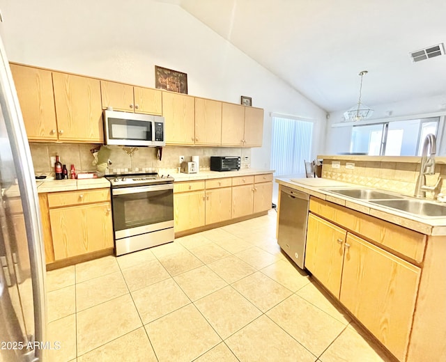 kitchen featuring appliances with stainless steel finishes, a sink, light brown cabinets, backsplash, and high vaulted ceiling
