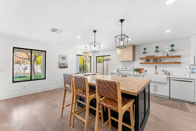 kitchen featuring sink, a breakfast bar area, white cabinets, a center island, and white appliances