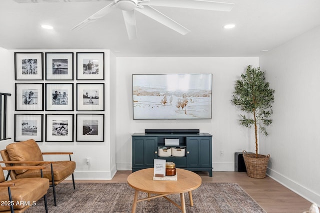 living area with hardwood / wood-style floors and ceiling fan