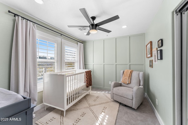 bedroom featuring a crib, light colored carpet, and ceiling fan