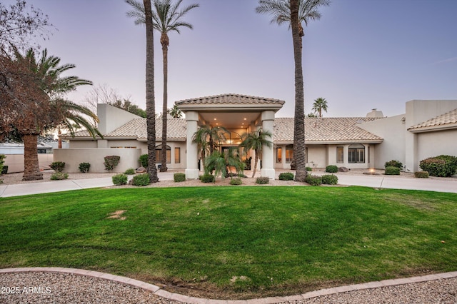 mediterranean / spanish house with a balcony and a lawn