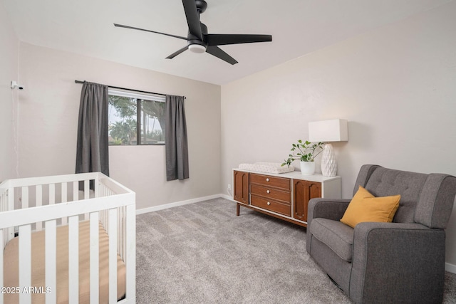 carpeted bedroom featuring ceiling fan and a crib