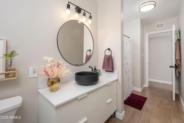 bathroom featuring vanity, wood-type flooring, and toilet