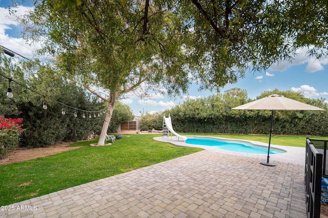 view of swimming pool with a lawn, a patio area, and a water slide