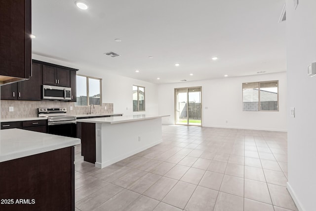 kitchen featuring a kitchen island, stainless steel appliances, tasteful backsplash, sink, and light tile patterned floors