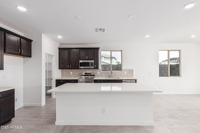 kitchen featuring dark brown cabinetry, appliances with stainless steel finishes, sink, and a kitchen island