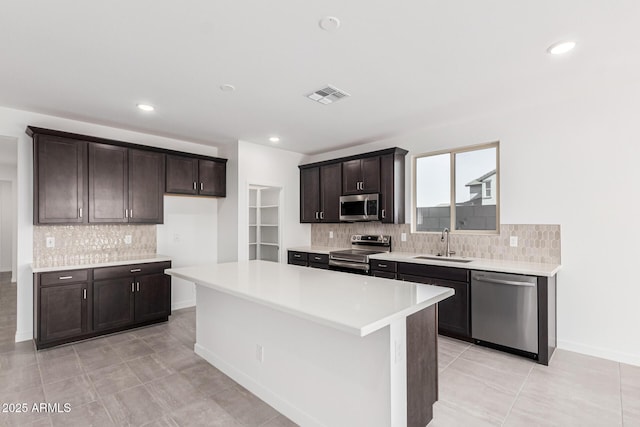 kitchen featuring sink, appliances with stainless steel finishes, a center island, and dark brown cabinets