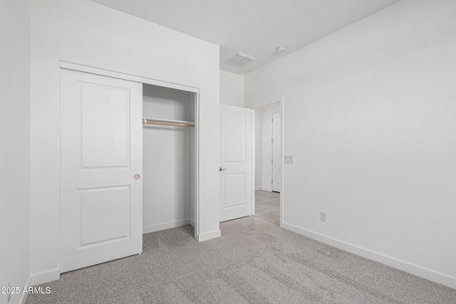 unfurnished bedroom featuring light colored carpet and a closet