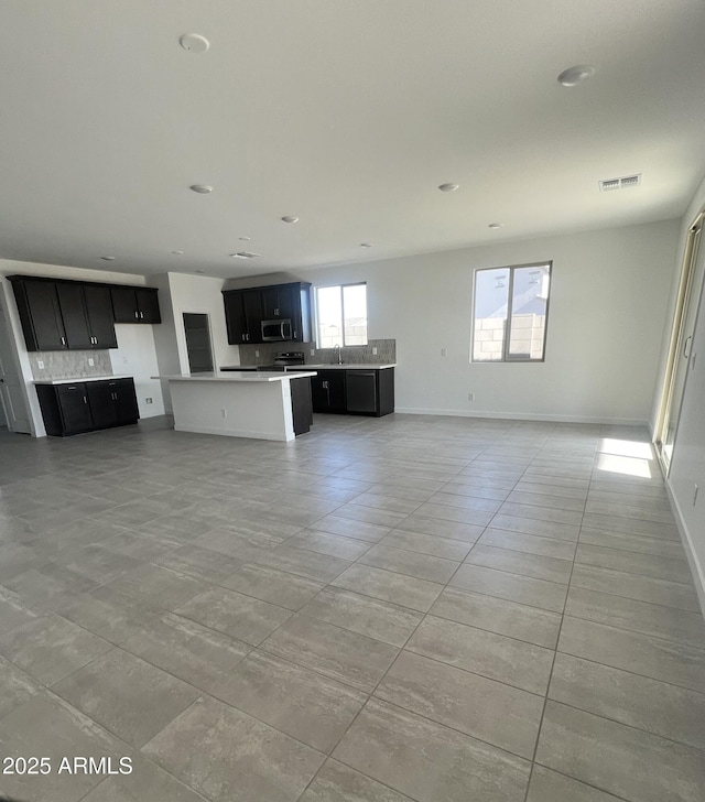 unfurnished living room featuring light tile patterned floors, a healthy amount of sunlight, and sink