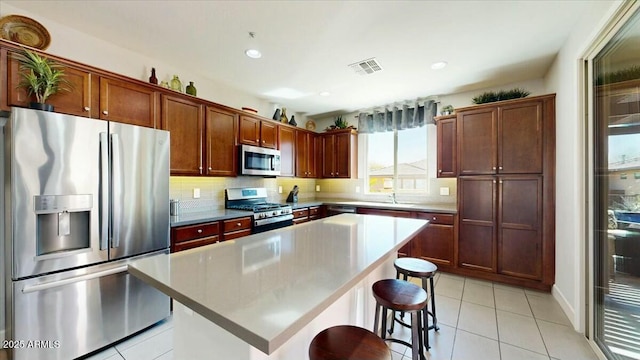 kitchen with decorative backsplash, stainless steel appliances, a kitchen island, a breakfast bar area, and light tile patterned floors
