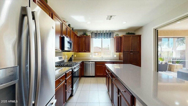 kitchen with light tile patterned flooring, a sink, appliances with stainless steel finishes, visible vents, and decorative backsplash