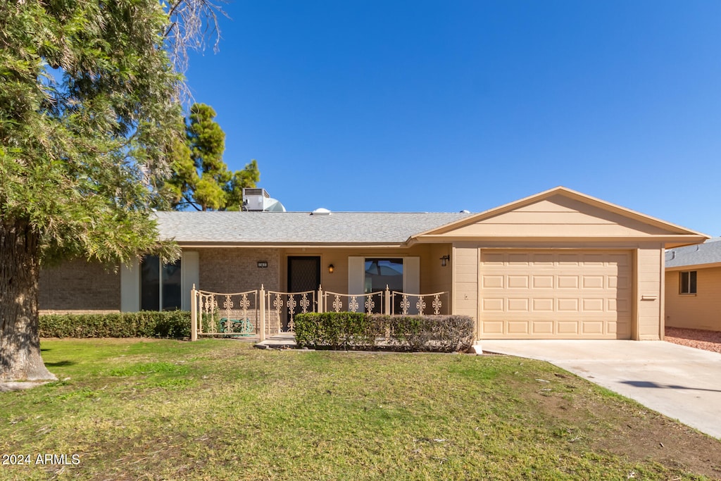 ranch-style house featuring a garage and a front lawn