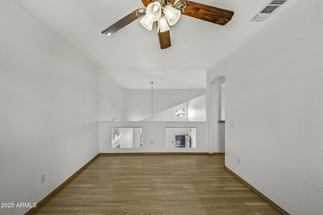 4530 E Desert Wind Dr, Phoenix, AZ 85044 - unfurnished living room with ceiling fan, wood finished floors, baseboards, lofted ceiling, and arched walkways