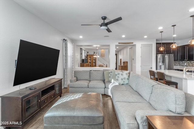 living room featuring hardwood / wood-style flooring, ceiling fan, and sink