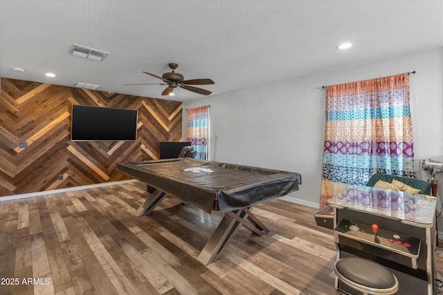 recreation room featuring ceiling fan, wooden walls, and wood-type flooring