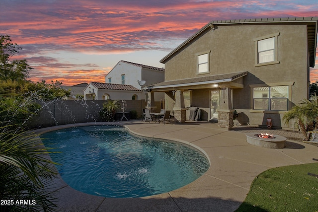 pool at dusk with a patio and an outdoor fire pit