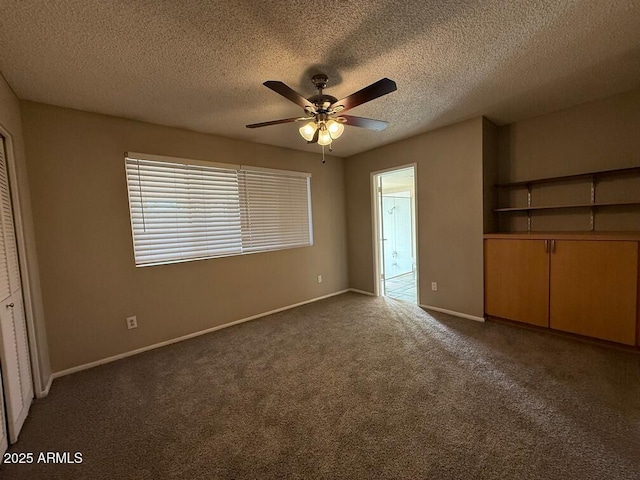 unfurnished bedroom with dark colored carpet, connected bathroom, ceiling fan, and a textured ceiling