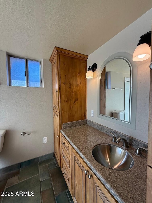 bathroom with vanity, toilet, and a textured ceiling