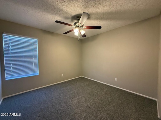 spare room with a textured ceiling, ceiling fan, and dark colored carpet