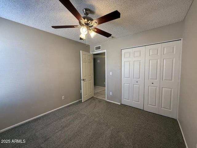 unfurnished bedroom with ceiling fan, a closet, dark carpet, and a textured ceiling