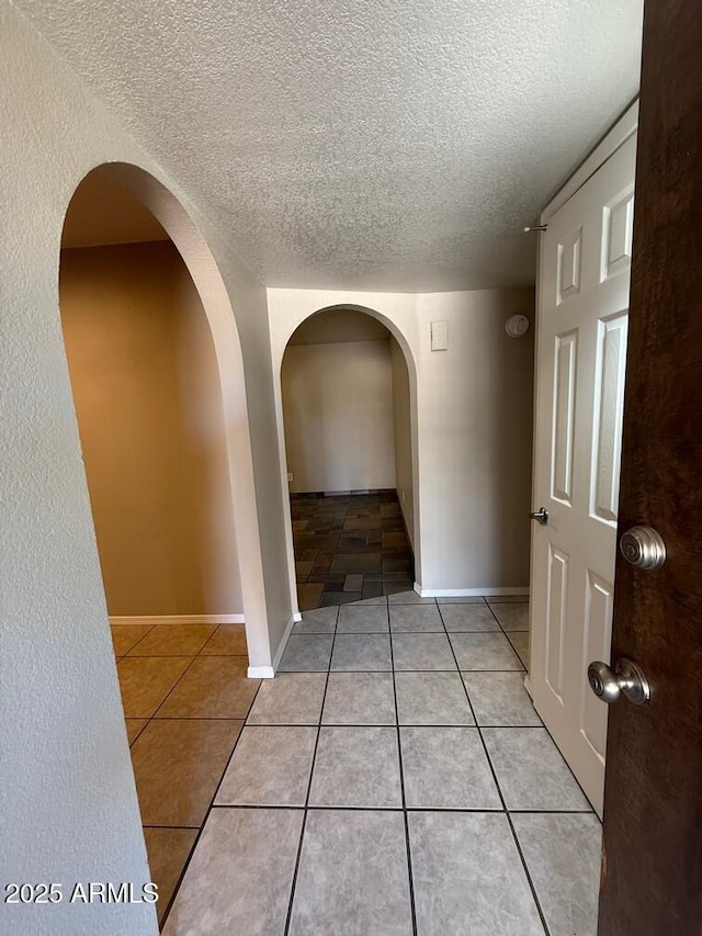 hallway with light tile patterned floors and a textured ceiling