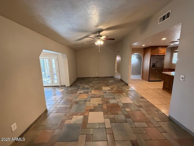 interior space with ceiling fan, lofted ceiling, a textured ceiling, and a wealth of natural light