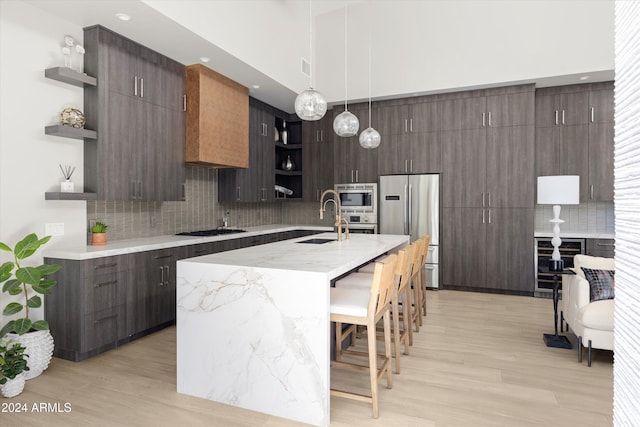 kitchen featuring sink, stainless steel appliances, decorative light fixtures, decorative backsplash, and a breakfast bar area