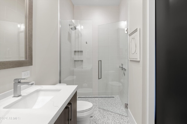 bathroom with toilet, vanity, and a shower with door