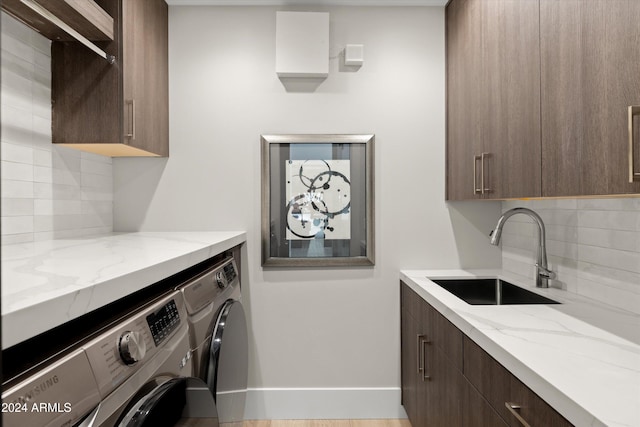 washroom with cabinets, sink, washer and clothes dryer, and light hardwood / wood-style floors