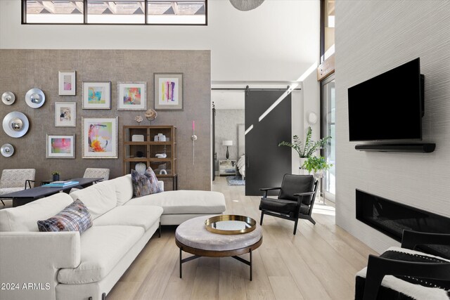 6525 E Cave Creek Rd Unit 6, Cave Creek, AZ 85331 - living area featuring a towering ceiling, a barn door, a glass covered fireplace, and light wood finished floors
