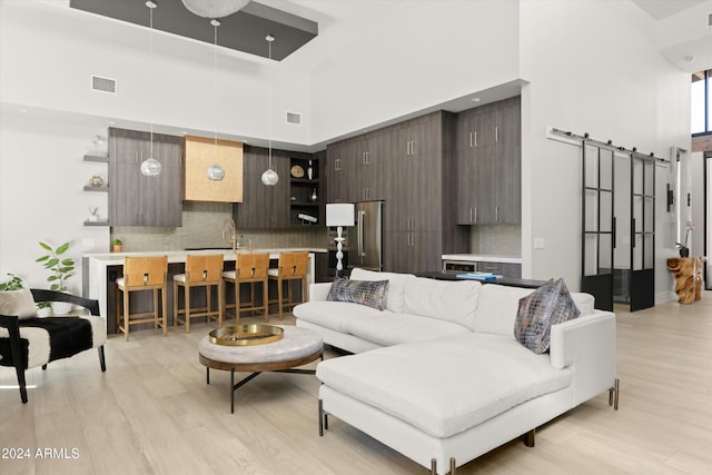 living room with a towering ceiling, light hardwood / wood-style flooring, and a barn door