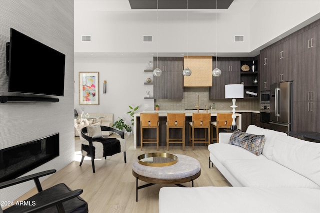 living room featuring sink, a towering ceiling, and light hardwood / wood-style flooring