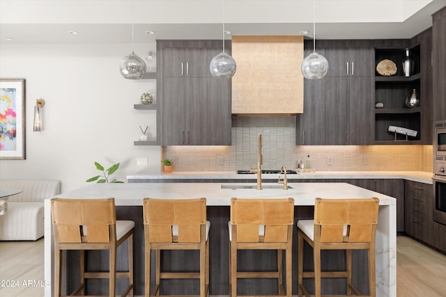 kitchen featuring light stone countertops, appliances with stainless steel finishes, a kitchen bar, light wood-type flooring, and backsplash