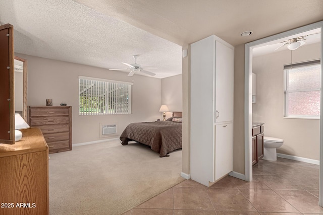 carpeted bedroom featuring ceiling fan, a textured ceiling, and ensuite bath