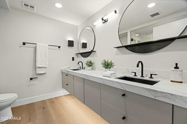 bathroom featuring wood finished floors, a sink, and visible vents