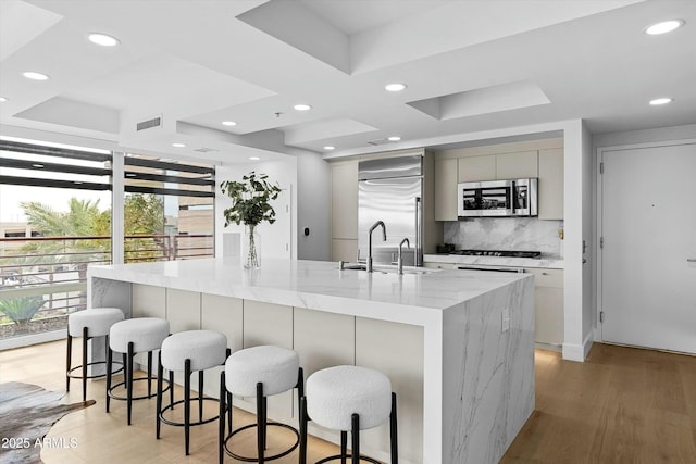 kitchen featuring tasteful backsplash, a large island, modern cabinets, appliances with stainless steel finishes, and a sink