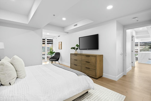 bedroom featuring baseboards, a tray ceiling, light wood finished floors, and recessed lighting