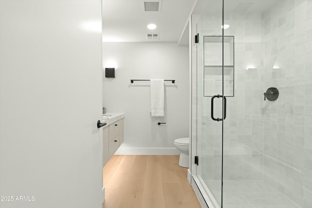 bathroom with vanity, wood finished floors, visible vents, and a shower stall