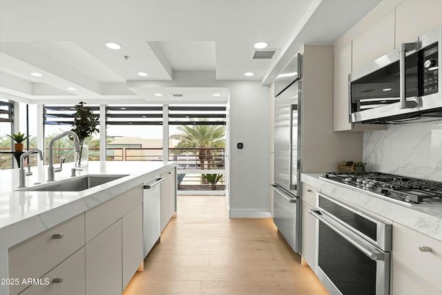 kitchen featuring stainless steel appliances, a wealth of natural light, a sink, and tasteful backsplash