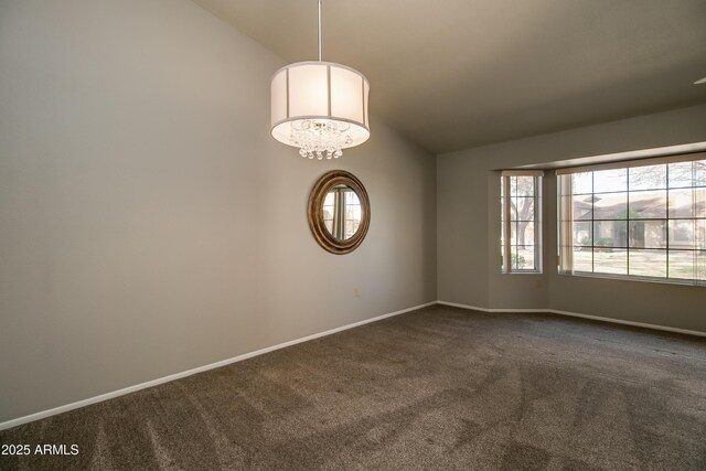 empty room with lofted ceiling, dark carpet, and a notable chandelier