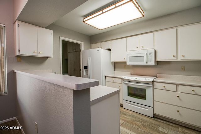 kitchen with white cabinetry, white appliances, kitchen peninsula, and light hardwood / wood-style flooring