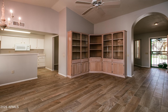 unfurnished living room featuring high vaulted ceiling, ceiling fan with notable chandelier, and dark hardwood / wood-style flooring