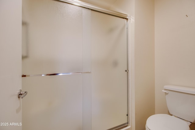 bathroom featuring toilet and a shower with shower door