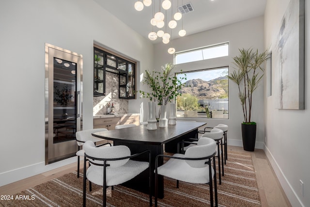 dining area with a mountain view, light hardwood / wood-style floors, a chandelier, and beverage cooler