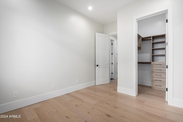 unfurnished bedroom with light hardwood / wood-style floors, a spacious closet, and a closet