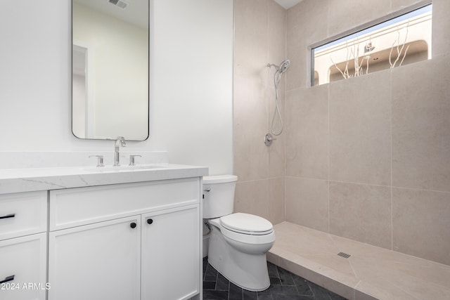 bathroom with toilet, vanity, and tiled shower