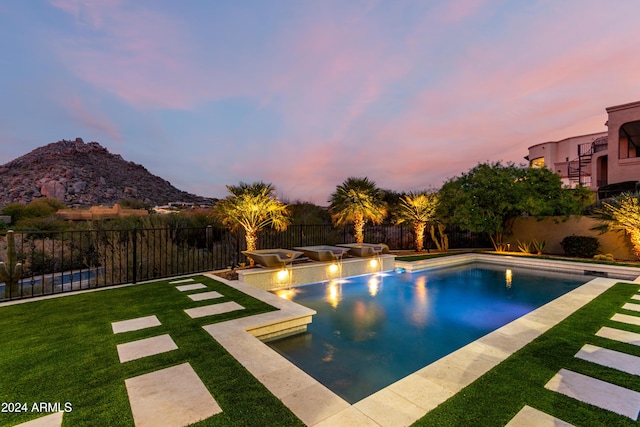 pool at dusk with a mountain view and a yard